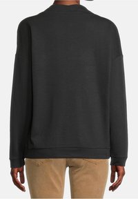 Czarna bluza o luźnym kroju, z opuszczonymi ramionami i okrągłym dekoltem. Wykonana z miękkiego materiału z minimalnymi przeszyciami.