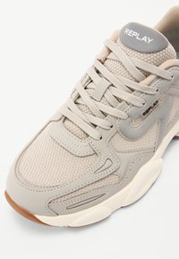 Beige sportieve schoen met een bovenwerk van mesh en leer, ronde neus, veterontwerp en rubberen zool. Voorzien van de "REPLAY" branding op de tong.