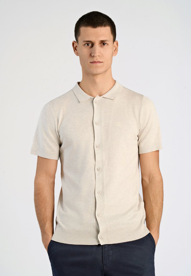 Ljusbeige kortärmad polo med knäppning framtill, ribbad krage och fåll; slät textur; subtilt broderad logotyp på bröstet.
