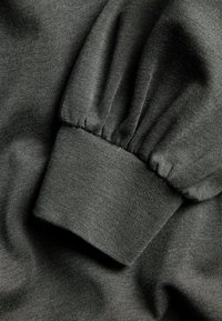 Ciemnoszara tkaninowa rękawica z elastycznym mankietem i szczegółami marszczenia, ukazująca teksturę i fałdy miękkiego dzianinowego materiału.