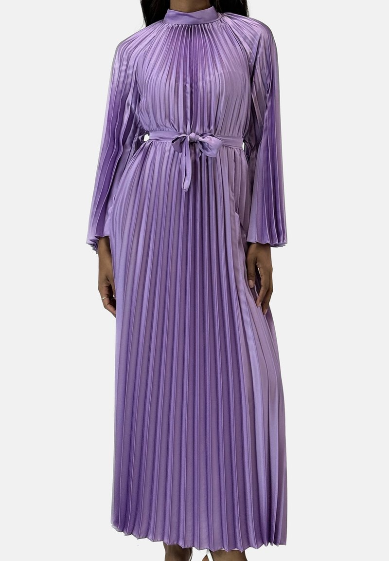 Lang, plisseret kjole i lys lilla med lange ærmer og høj halsudskæring. Inkluderer et matchende bælte i taljen for faconsyling.