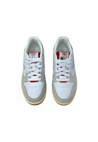 Sneaker bianche con accenti in suede grigio, punta forata, etichetta rossa sulla linguetta e lacci bianchi; suola in gomma gialla.