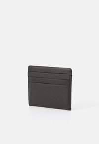 Tarjetero de cuero negro con un acabado texturizado, que cuenta con cuatro ranuras para tarjetas y un perfil delgado. Diseño minimalista, de forma rectangular.