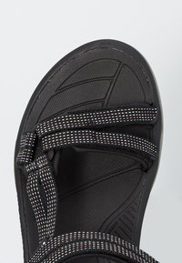 Czarne sportowe sandały z teksturowaną podeszwą, regulowane paski z kolorowym, plecionym wzorem, wyściełana wkładka dla wygody.