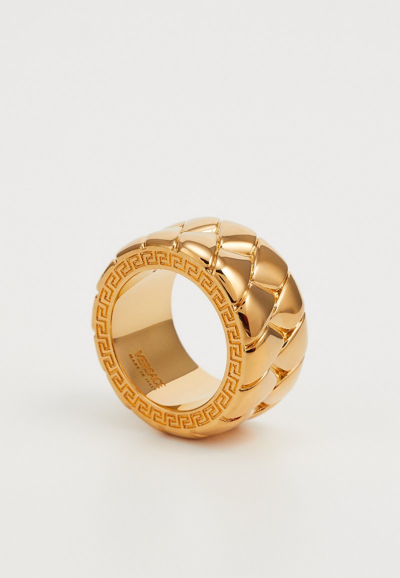 Anillo de color dorado con un diseño trenzado, que presenta una superficie lisa y pulida, y un patrón de clave griega grabado en la banda interior.