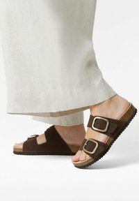 Barna szarvasbőr szandál két széles pánttal és fém csatokkal, parafa talppal és texturált gumitalppal.