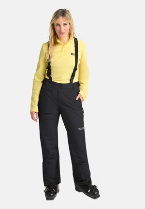 Zwarte sneeuwbroeken met verstelbare bretels, ritszakken en een getailleerd silhouet, gecombineerd met een lichtgewicht gele rits-top.