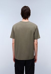 Tricou scurt, de culoare verde măslin, cu mâneci scurte și guler rotund; fabricat din bumbac moale; croială lejeră; textură netedă; design minimalist, fără modele vizibile.