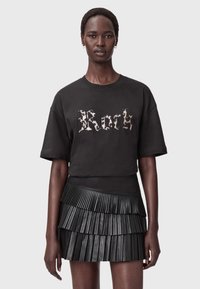 Mustapaita, jossa on "Rock" heijastavilla kirjaimilla, yhdistettynä mustaan, laskostettuun nahkaminihameeseen, jossa on kerroksellisia tasoja.