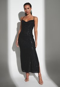 Abito nero con paillettes, scollo ampio, forma aderente e spacchi laterali. Spalline sottili regolabili e una texture liscia.