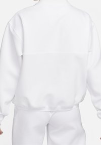 Valkoinen fleece-huppari, jossa on korkea kaula, tiputetut olkapäät ja ribatttu helma. Liukas pinta ja minimalistinen muotoilu.