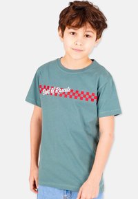Green cotton t-shirt featuring a red checkered pattern and "Band of Rascals" text across the chest. Short sleeves and round neckline.