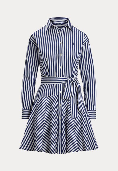 Zils un balts ar vertikālām svītrām garām piedurknēm krekla kleita ar pogām priekšpusē, apkakli, jostu viduklī un izplešamu svārku ar diagonālām svītrām.