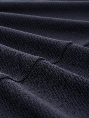 Tessuto di velluto blu scuro con una trama rigata, piegato a onde. Aspetto morbido con una leggera lucentezza e superficie uniforme.