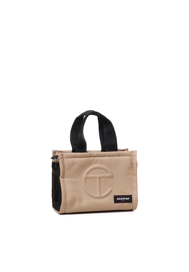 Kleine beige Tasche mit strukturierter Oberfläche, schwarzer Netzseite, kurzen schwarzen Griffen und geprägtem Logo auf der Vorderseite.
