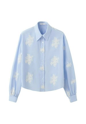 Camicia azzurra a maniche lunghe con bottoni e colletto appuntito, decorata con ricami floreali bianchi sparsi sul tessuto.