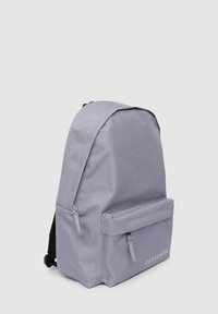 Zaino in tessuto grigio con una texture liscia, dotato di una tasca frontale e doppie cerniere laterali, logo del marchio stampato nella parte anteriore.