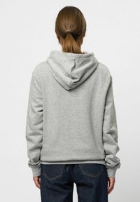 Grijze hoodie met een trekkoordcapuchon, gemaakt van zachte stof, met geribbelde manchetten en zoom, gedragen over donkere jeans. Achteraanzicht.