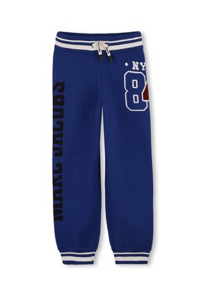 Pantalon de survêtement bleu avec taille élastique rayée blanche et poignets, cordon de serrage, et motifs de texte en noir et blanc incluant "NY" et "Marc Jacobs."