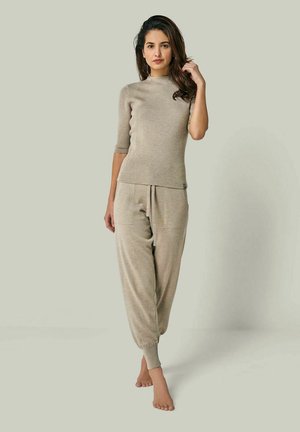 Beige ribbed knit top with a high neck and short sleeves paired with matching tapered joggers. Soft texture, elastic waistband, no visible fastenings.