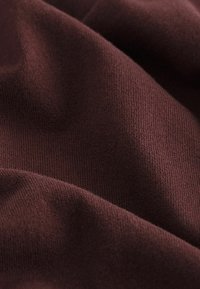 Burgunderfarbener Strickstoff mit einer glatten Textur, mittlerem Gewicht, dezentem Stretch und gleichmäßigem Stichmuster.