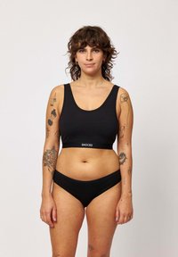 Zwarte katoenen sportbeha met een brede band waarop de merknaam "SNOCKS" staat, en bijpassende zwarte bikini slipjes. Gladde textuur, minimaal ontwerp.