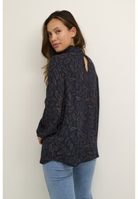 Marinebluse med paisley mønster i bronzetoner, lange ærmer, høj halsudskæring og en nøglehulåbning bagpå. Blødt stof.