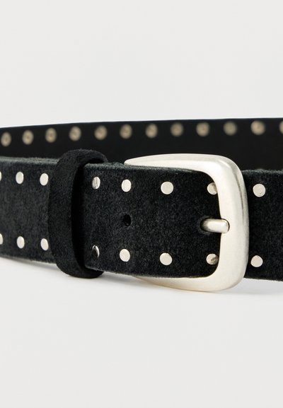 Ceinture en daim noir avec des clous ronds en argent, une boucle rectangulaire argentée et une boucle, sur un fond blanc uni.