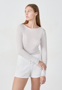 Jasnoz kolorowy długi rękaw z teksturowanym, prążkowanym wzorem, połączony z dopasowanymi teksturowanymi szortami z zapięciem na guzik.