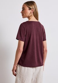 Camiseta de manga corta burdeos con escote redondo, confeccionada en una suave tela texturizada, con un corte relajado y un dobladillo curvado.