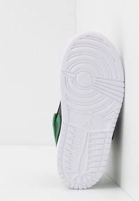 Sort sneakers med grønne accenter og en hvid, struktureret sål. Har en glat overflade og et tydeligt mønster på sålen.