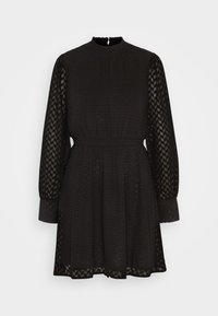 Robe mini noire à manches longues avec des manches en tulle à motifs, tissu texturé, taille ajustée et petit système de bouton à l'arrière sur un fond clair.