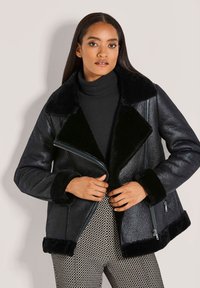 Zwarte bomberjack van imitatieleren met een kraag en manchetten van schapenvacht. Voorzien van zijritsen en een textuurafwerking, gecombineerd met een getailleerd ontwerp.