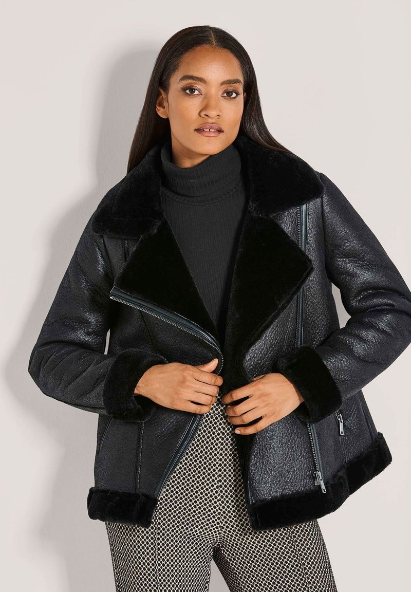 Zwarte bomberjack van imitatieleren met een kraag en manchetten van schapenvacht. Voorzien van zijritsen en een textuurafwerking, gecombineerd met een getailleerd ontwerp.