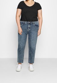 Camiseta negra de manga corta combinada con jeans de mezclilla claros de cintura alta, con corte recto y un ligero desgaste.