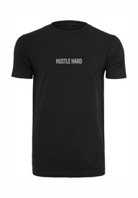 Svart bomull t-skjorte med teksten "HUSTLE HARD" i fet hvit skrift sentrert på brystet. Korte ermer, rund hals-design.