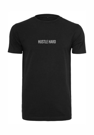 Maglietta nera in cotone con la frase "HUSTLE HARD" in grassetto bianco centrata sul petto. Maniche corte, design a girocollo.