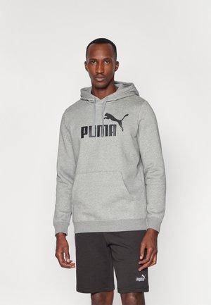 Grå hettegenser med en fremtredende svart Puma-logo, snorer og en frontlomme; kombinert med svarte shorts med en liten logo.