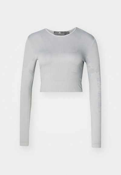Light gray long-sleeve crop top made of stretchy fabric, featuring textured patterns and a round neckline with a smooth finish.
