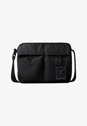 Μαύρη τσάντα crossbody Calvin Klein με ρυθμιζόμενο λουράκι, δύο μπροστινές τσέπες με φερμουάρ, διακριτικό λογότυπο και ετικέτα με το λογότυπο Calvin Klein.
