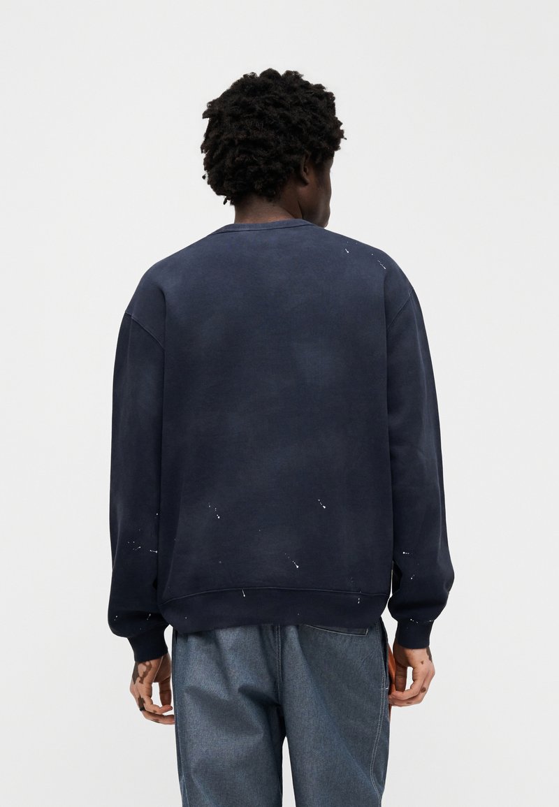 Marineblauer Sweatshirt mit lockerem Schnitt, einer strukturierten Oberfläche und weißen Farbspritzern. Gerippte Bündchen und Rundhalsausschnitt.