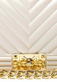 Borsa a tracolla in pelle bianca trapuntata con motivo a zigzag, hardware dorato e una catena spessa con accenti decorativi.