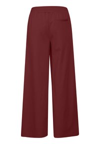 Bordeaux wijde broek met elastische tailleband en één achterzak, gezien vanuit de achterkant.