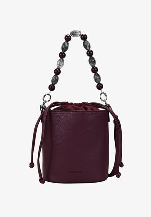 Bolso tipo bucket de cuero burdeos con cierre de cordón y asa decorativa de cuentas. Textura suave con un sutil detalle de grano.