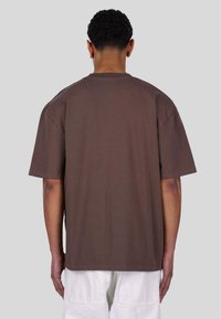 Brown oversized t-shirt made of cotton, featuring short sleeves, a round neckline, and a plain design with a relaxed fit.