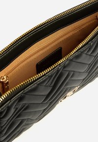 Pochette in pelle nera trapuntata con dettagli in oro, chiusura a zip e interno beige. Presenta un esterno texturizzato e più scomparti.