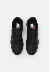 Sneaker nere con tomaia in pelle liscia, punta perforata e lacci neri. Presenta una linguetta con marchio e colori accentuati sottili in rosso, bianco e blu.