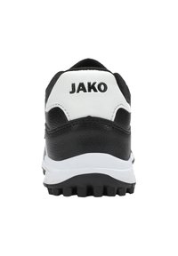 Chaussure de sport noir et blanc avec un dessus en cuir texturé, un logo "JAKO" bien visible et une semelle intermédiaire blanche épaisse avec une semelle extérieure antidérapante.