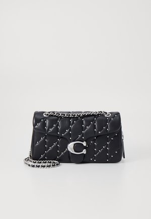 Černá prošívaná kožená kabelka se stříbrnými hřebíčky a stříbrným řetízkovým popruhem, vybavená výrazným stříbrným uzávěrem ve tvaru písmene "C".