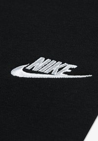 Zwarte stof met een prominent geborduurd wit Nike-logo, met een soepele textuur en een klassieke geometrische vorm.